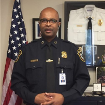 A police officer standing in front of an american flag.