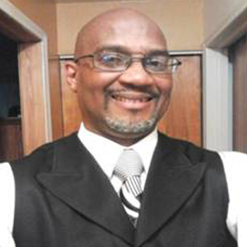 A man in vest and tie smiling for the camera.