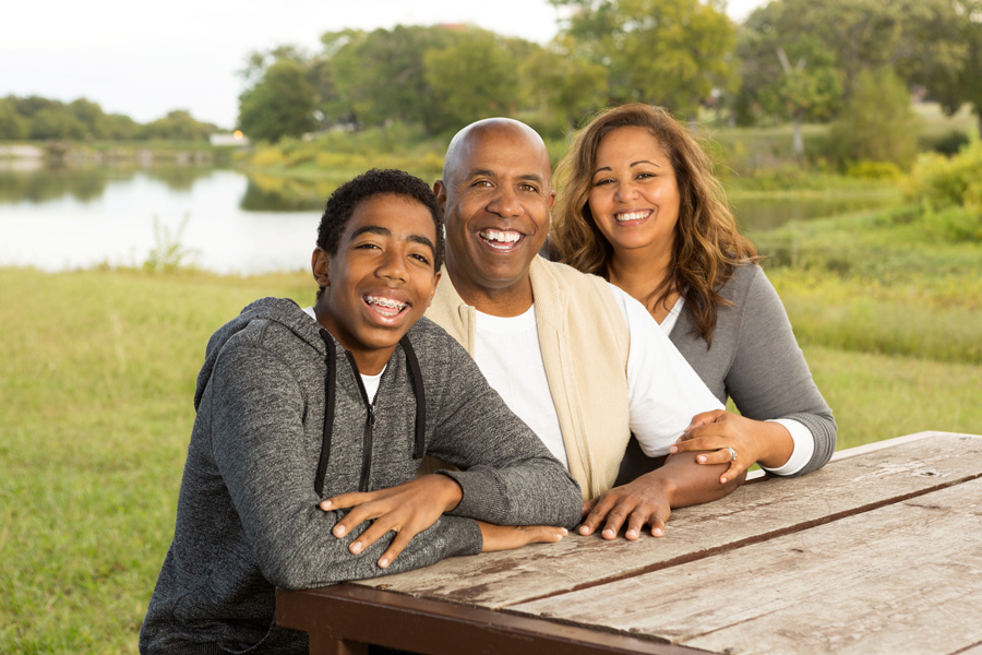 A family sitting at the table outside in the sun.