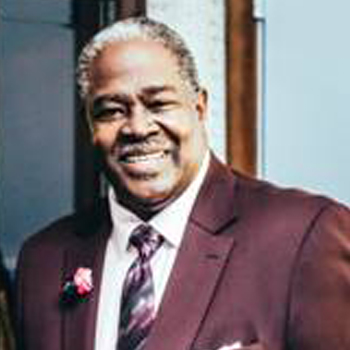 A man in a suit and tie smiling for the camera.