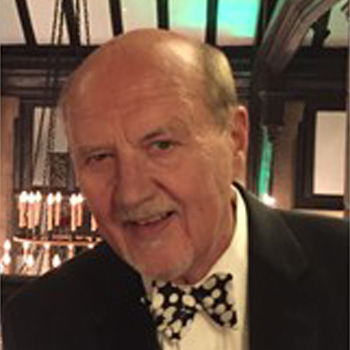 A man with a bow tie in front of a bar.