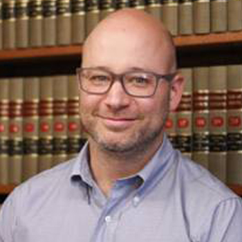 A man in front of some books and shelves