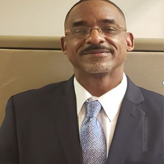 A man in a suit and tie standing next to a wall.