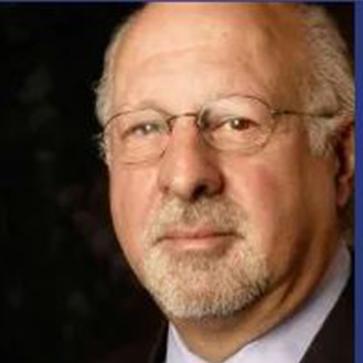 A man with glasses and a beard wearing a suit.