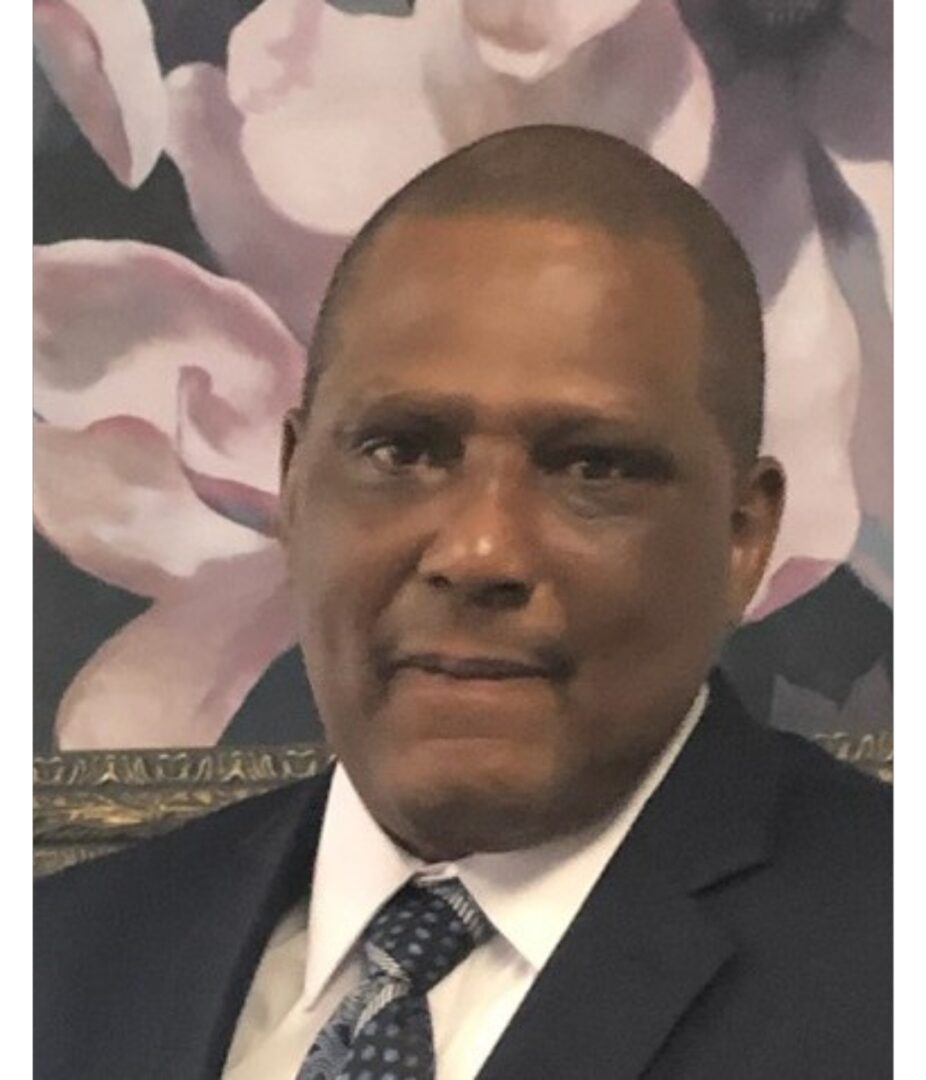 A man in suit and tie standing next to flowers.