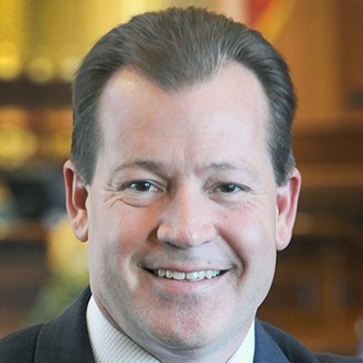 A man in suit and tie smiling for the camera.